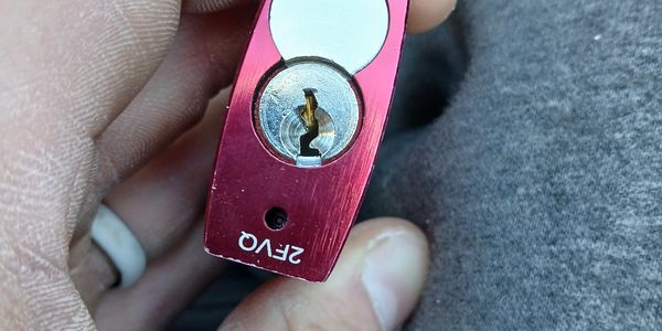 Hand holding a red ZFVO padlock with a circular keyhole.